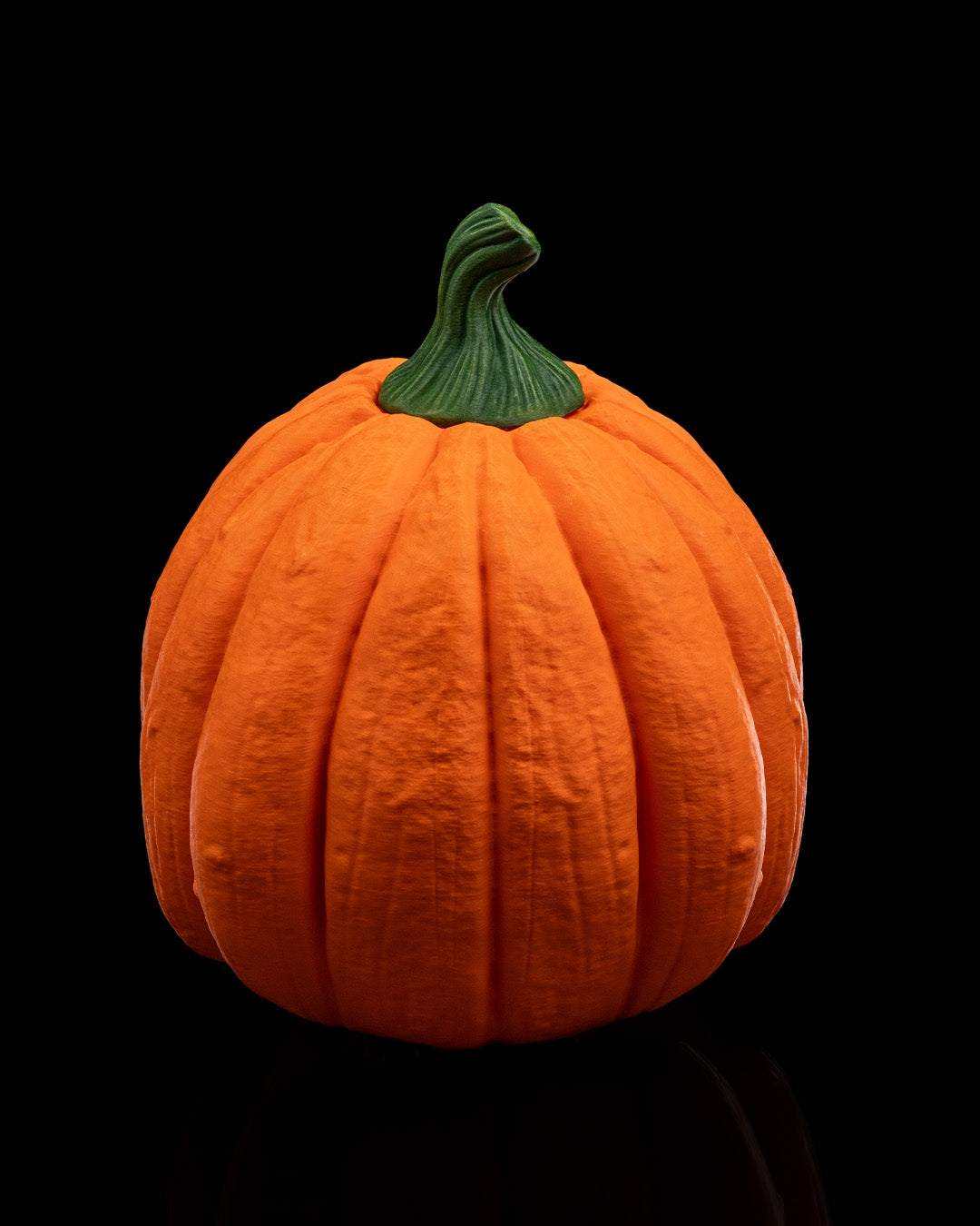 Pumpkin Head Mask in bright orange with sculpted vertical grooves and a dark green curved stem, resembling a traditional pumpkin.