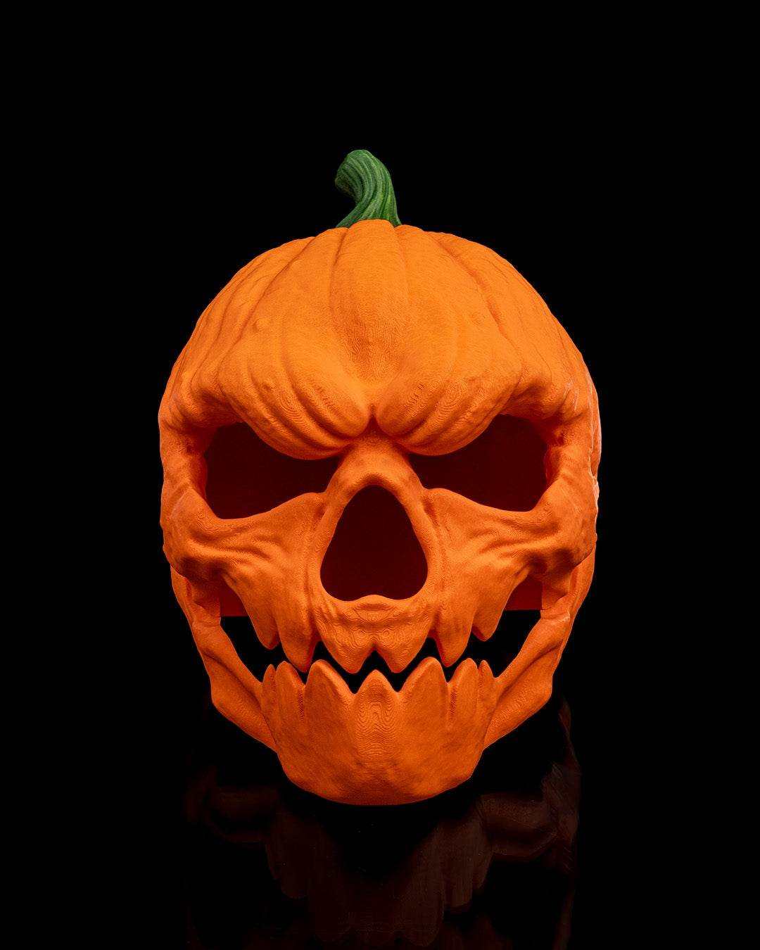 Pumpkin Head Mask in textured orange with a green stem, featuring deep eye and nose holes and jagged teeth