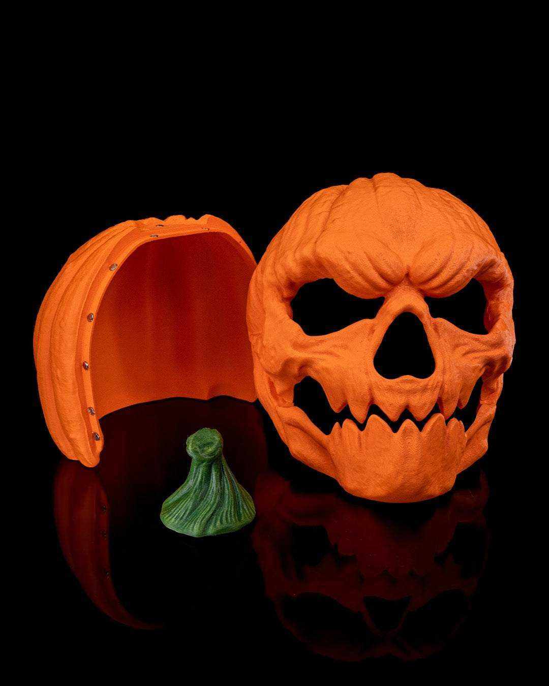 Pumpkin Head Mask in textured orange pumpkin material with jagged skull-like eye and mouth openings, shown with green stem