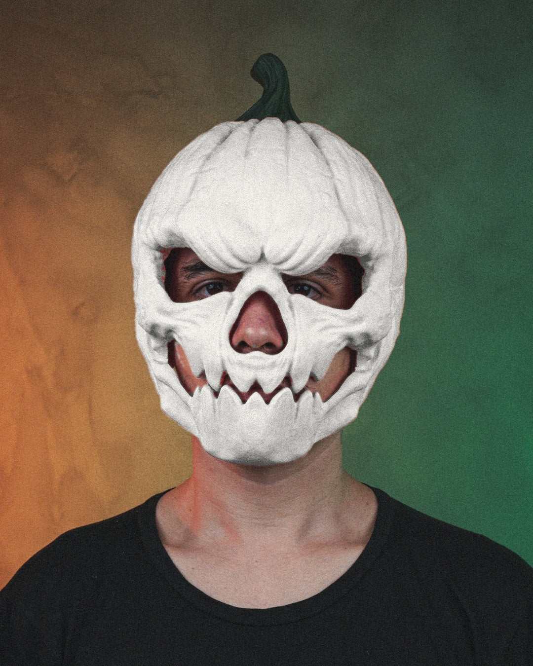 Pumpkin Head Mask in white with a dark green stem, carved skull face, deep eye openings and jagged teeth